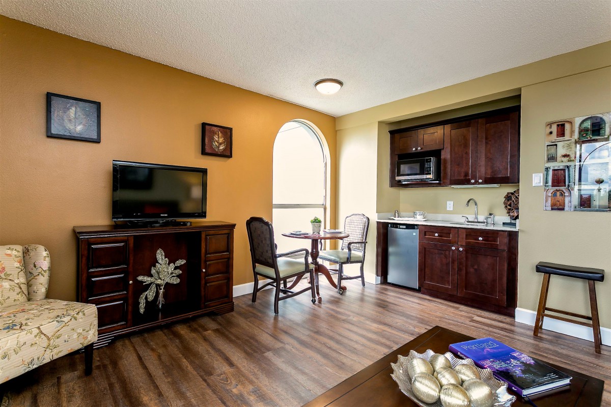A cozy living space featuring a kitchenette and dining area, complete with wooden floors and modern decor.