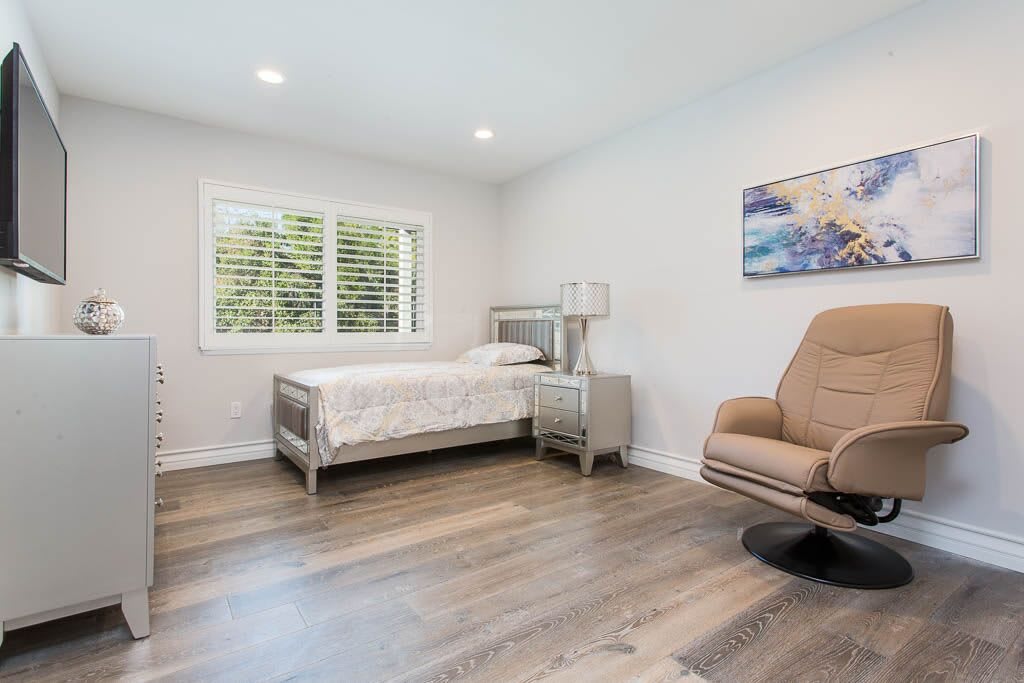 A minimalist bedroom featuring a single bed, modern chair, and soft lighting.