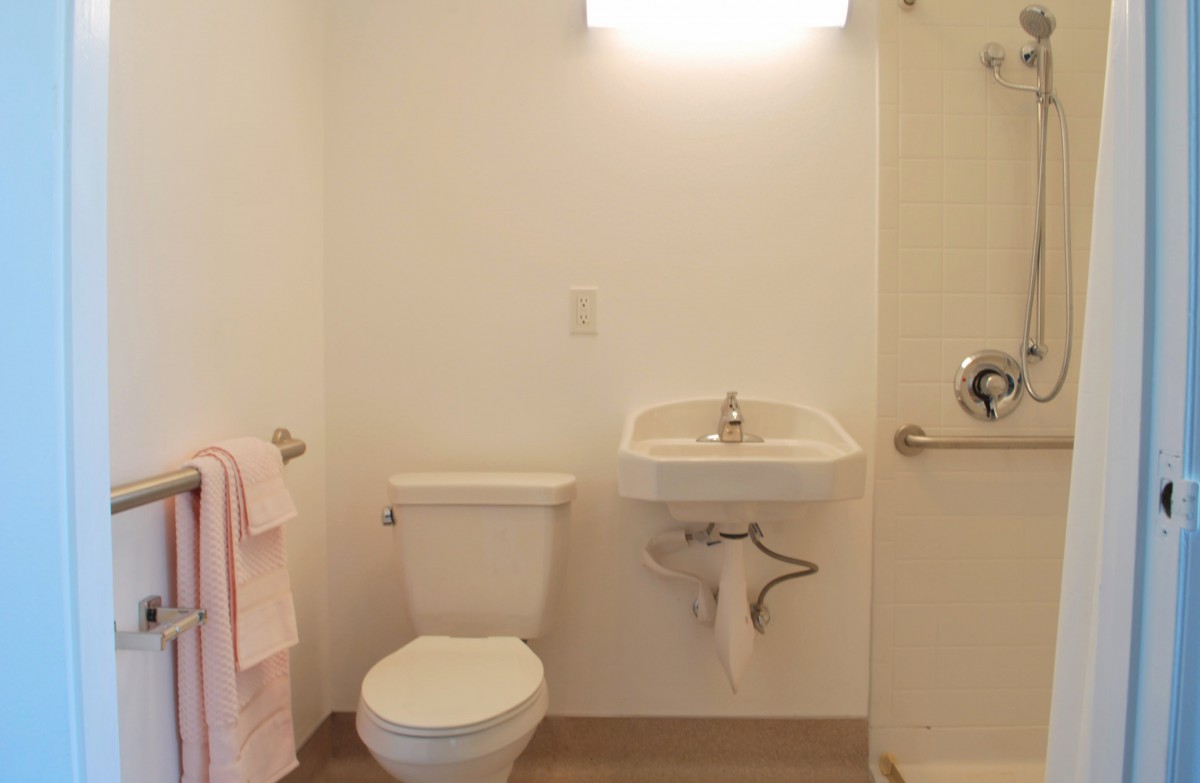 A minimalist bathroom with a toilet, sink, and towel rack.