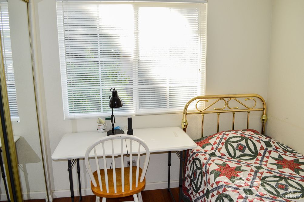 A cozy bedroom corner with a desk and chair next to a patterned bed.