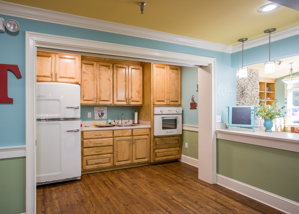 A vintage-style kitchen with wood cabinets and a retro white refrigerator.