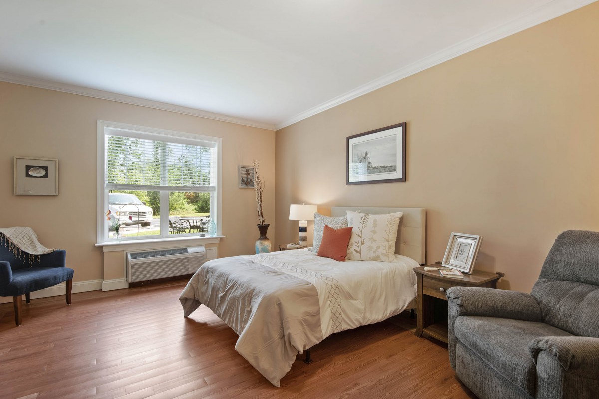 A modern bedroom with a cozy bed, large window, and stylish decor.