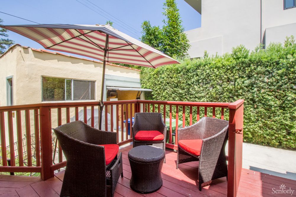 A cozy patio setup with wicker chairs and a table under a striped umbrella.