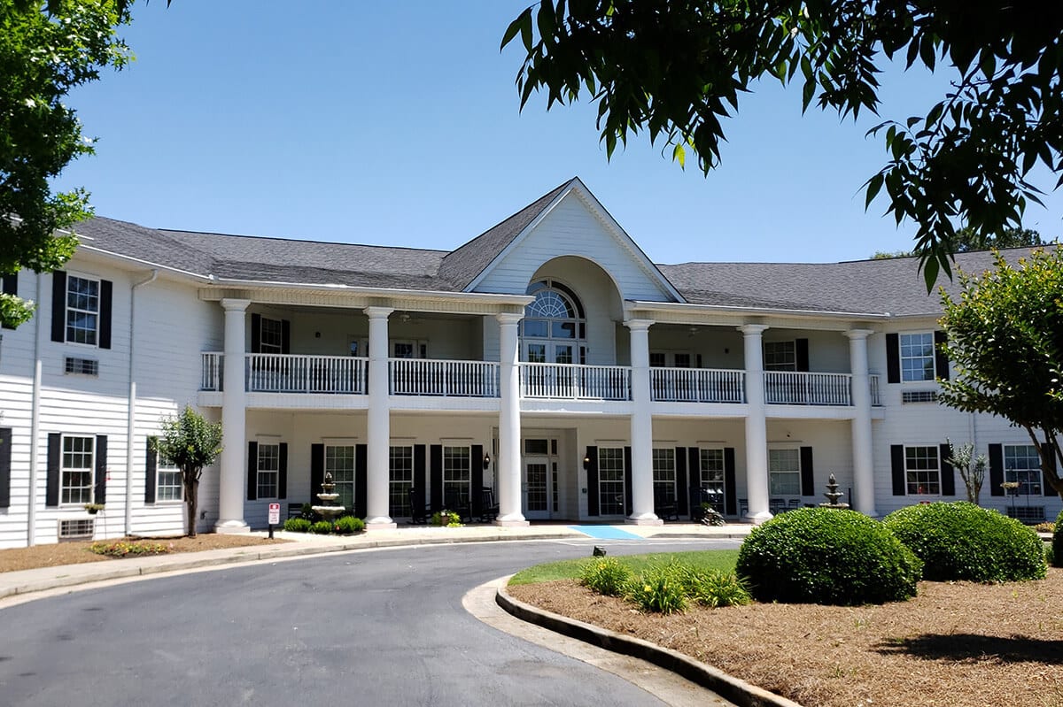 A grand colonial-style building with prominent columns and a symmetrical facade, surrounded by landscaped greenery.
