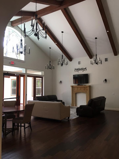 A spacious living room featuring high ceilings, elegant chandeliers, and a cozy fireplace.