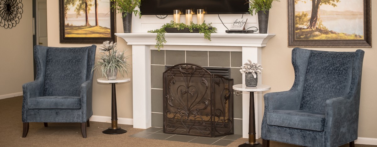 Elegant living room fireplace with decorative candles and plants on the mantel.