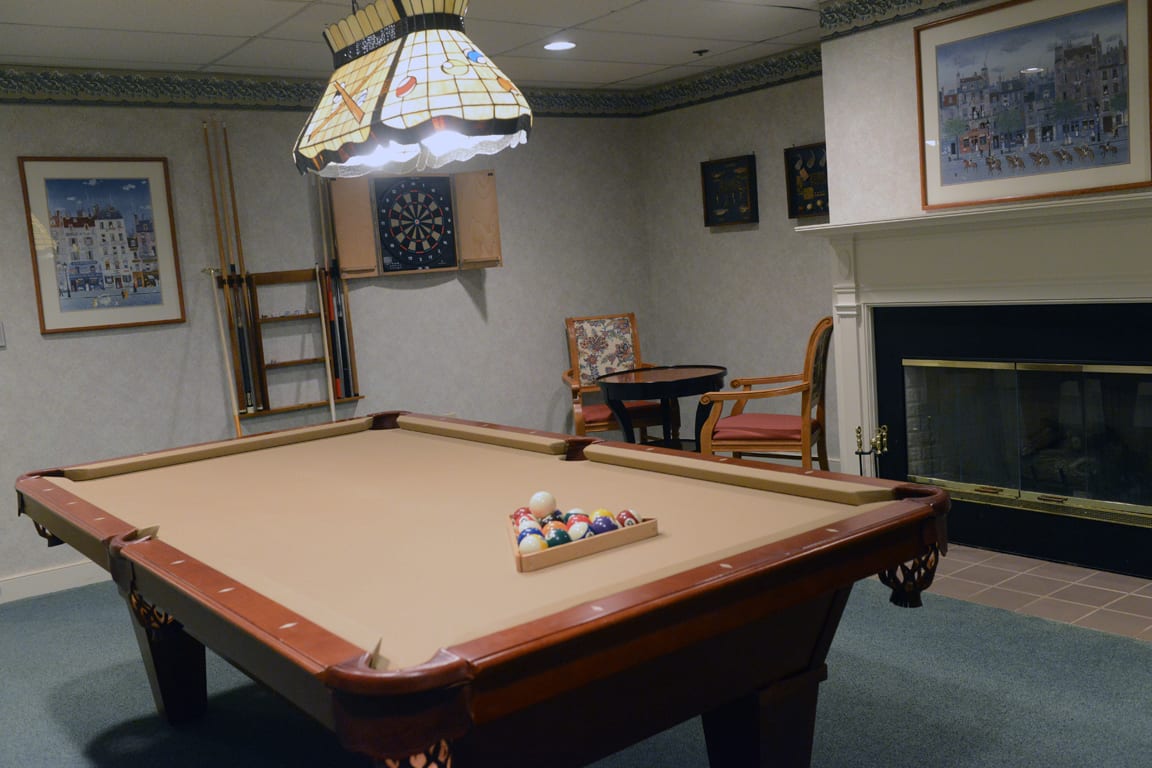 A cozy game room featuring a billiards table and a dartboard on the wall.