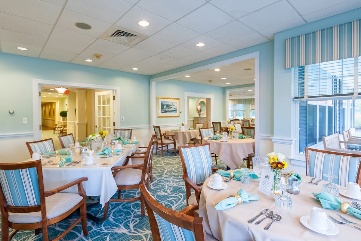 An elegantly decorated dining room with neatly arranged tables and chairs, set for a meal.