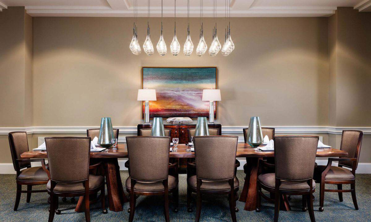 Elegant dining room with a large table, stylish chairs, a modern chandelier, and vibrant artwork.