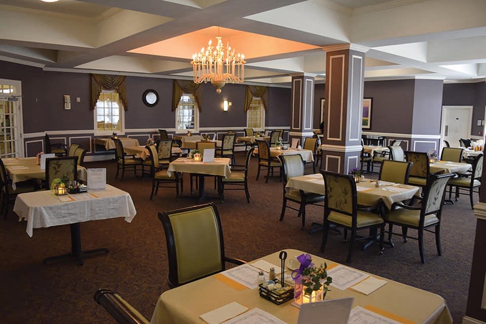 A well-decorated dining room with neatly arranged tables and a chandelier.