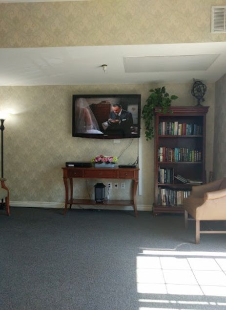 A cozy living room with a television, bookshelf, and comfortable seating.