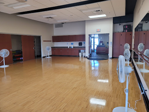 A spacious and well-lit gym area with polished wooden flooring, ready for various fitness activities.