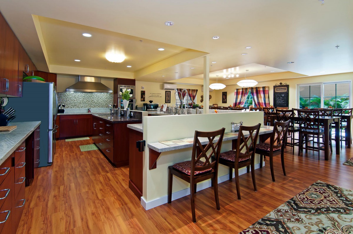 A modern kitchen interior featuring a spacious layout with bar stools and wooden flooring.