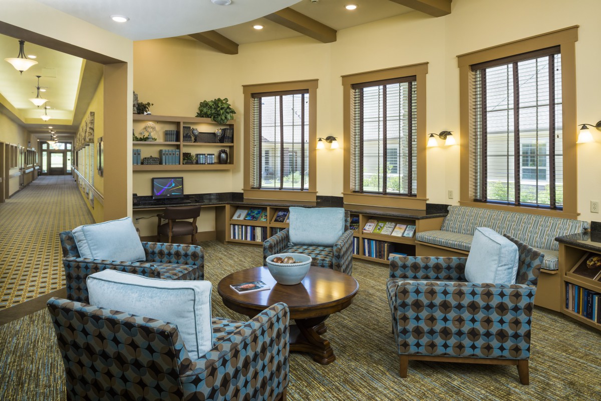 A cozy living room with comfortable seating, bookshelves, and large windows.