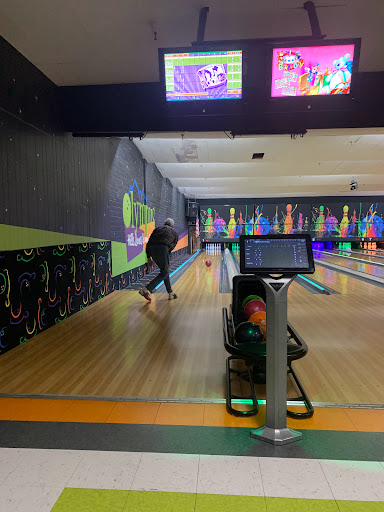 A person enjoying a game of bowling in a vibrant, illuminated bowling alley.