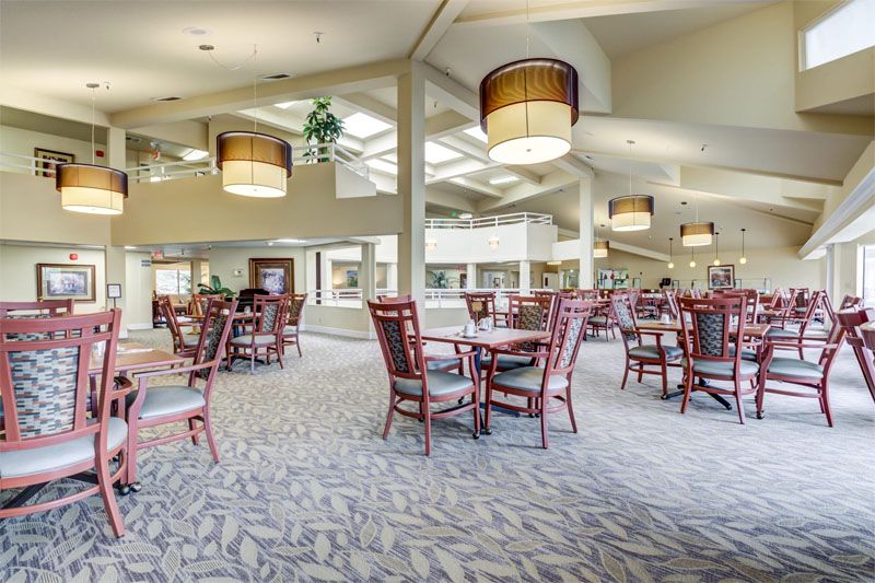 A spacious dining area with multiple tables and chairs, featuring modern ceiling lights and a bright atmosphere.