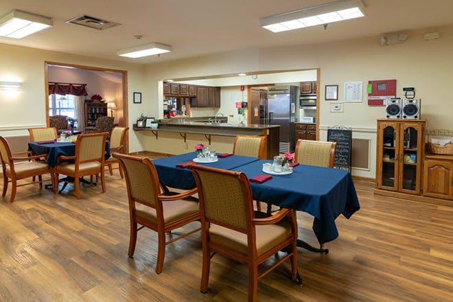A cozy dining area with tables and chairs, adjacent to a kitchen space.