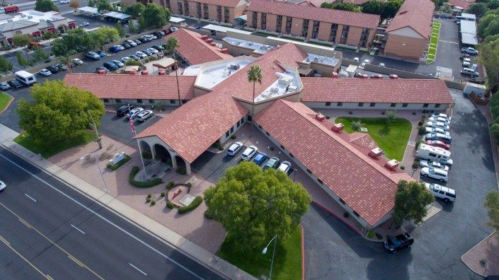 Aerial view of a building complex with a parking lot and adjacent road.