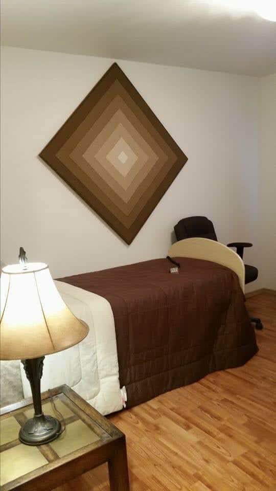 A cozy massage room with a table, lamp, and wall decor.