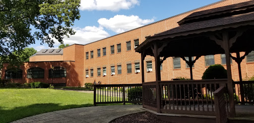 A serene view of a brick building alongside a gazebo, set against a clear blue sky.