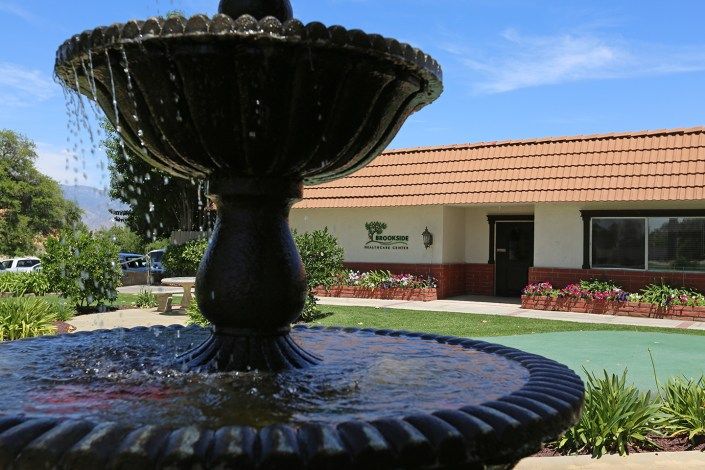 A scenic view of a fountain in the foreground with a building in the background on a sunny day.