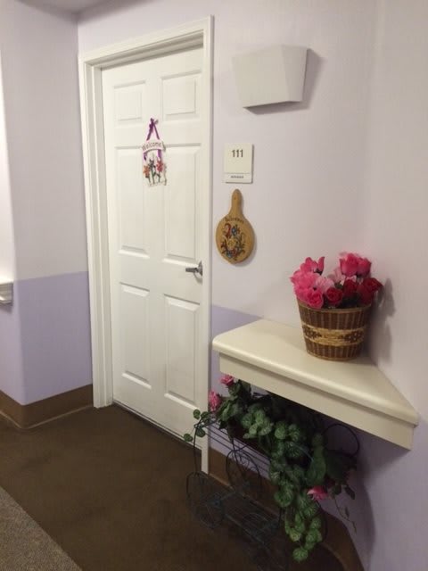 A decorated hallway with a door and a basket of flowers on a shelf.