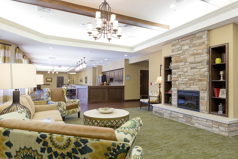 A spacious and well-lit lobby area with comfortable seating, a fireplace, and a chandelier, providing a welcoming atmosphere.
