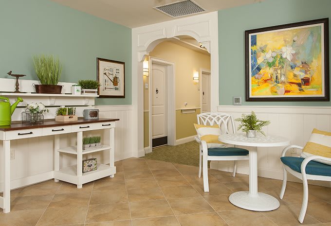 A cozy interior with a small round table, colorful artwork on the wall, and decorative plants.