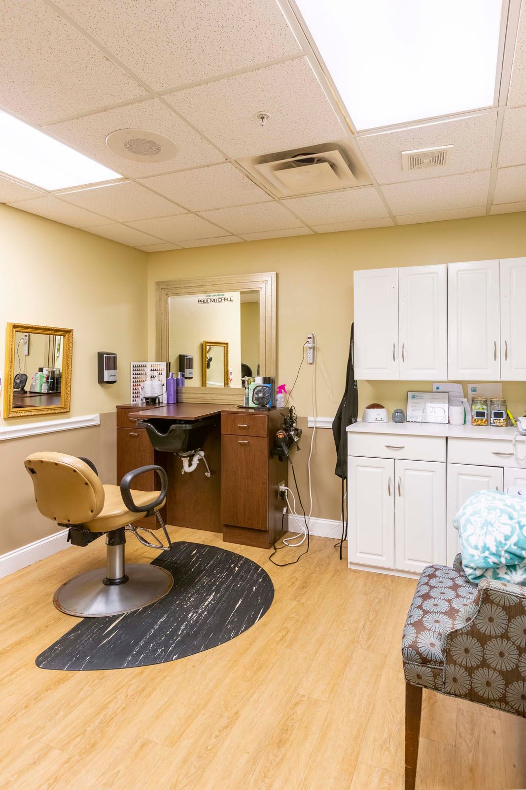 A cozy hair salon setup with a styling chair, mirror, and cabinets.
