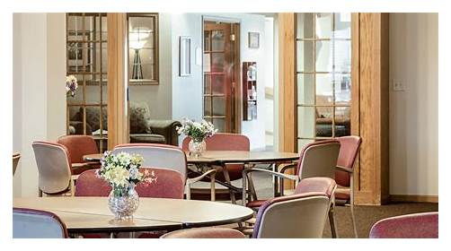 A cozy seating area featuring tables and chairs, adorned with fresh flowers, inviting a sense of relaxation.