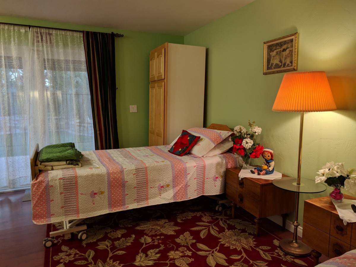 A cozy bedroom with a single bed, bedside table, and a floor lamp.