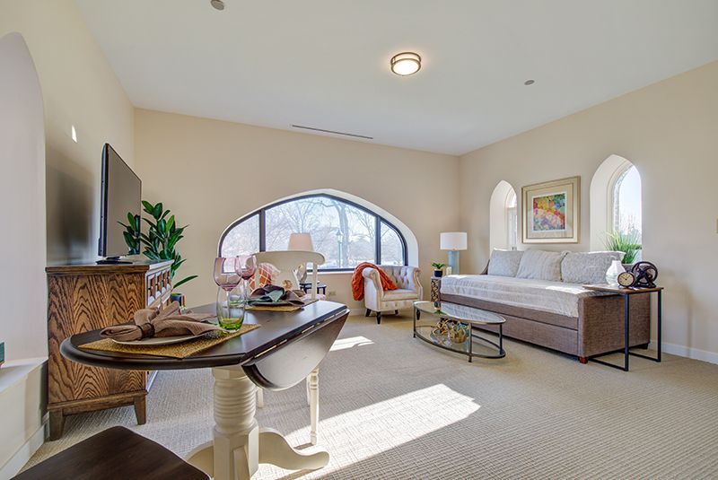 A warmly lit living room with elegant furnishings and a large arched window.