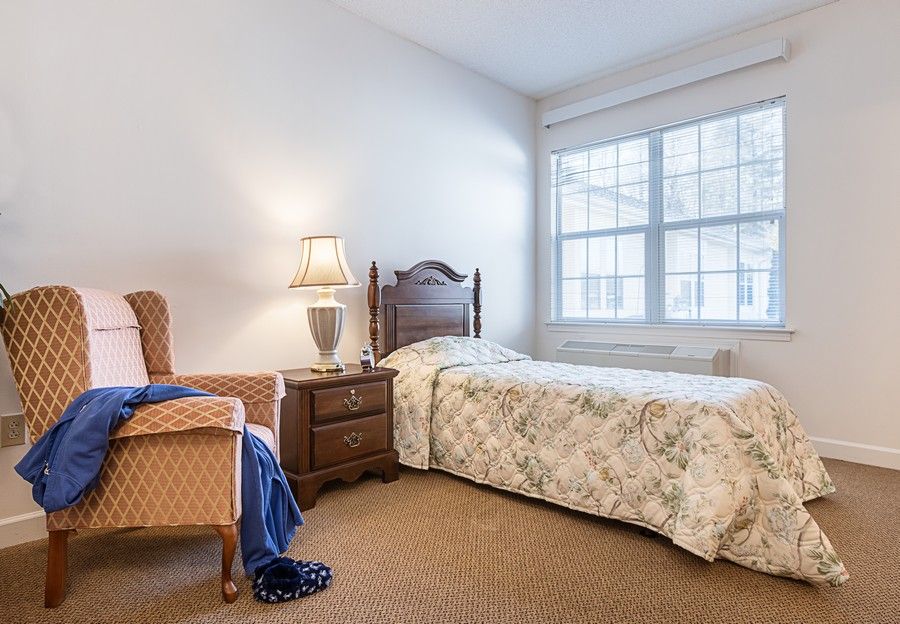 A cozy bedroom with a single bed, armchair, and large window allowing natural light to fill the space.