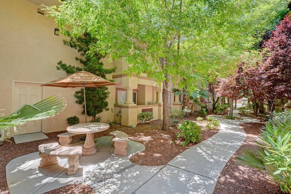 A serene garden area with outdoor seating and a winding pathway surrounded by lush greenery.