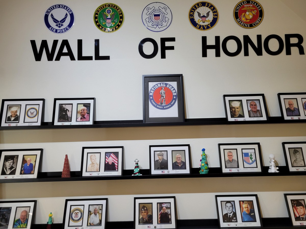 A Wall of Honor featuring framed photos of veterans and military emblems representing different branches.