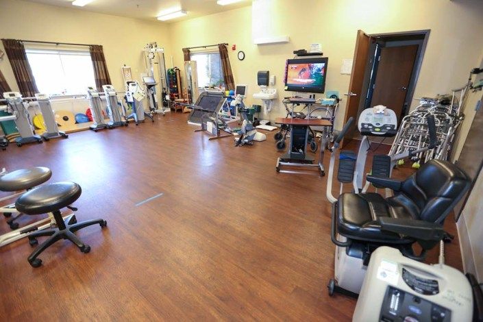 A spacious physical therapy room equipped with various exercise machines and rehabilitation tools.