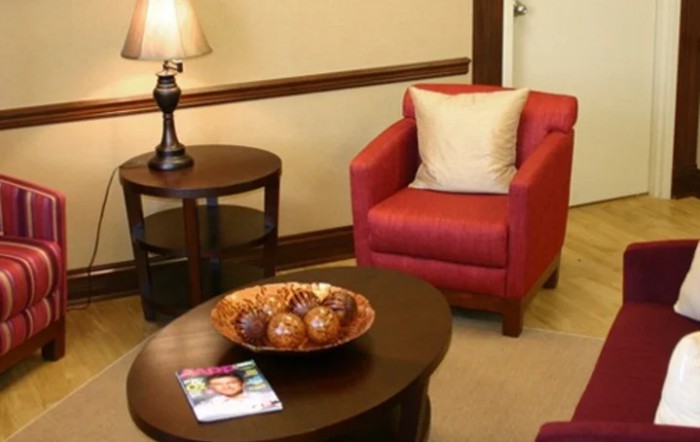 A cozy living room setup with a red armchair, side table with a lamp, and a coffee table with decorative items.