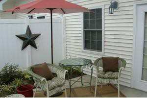 A cozy outdoor patio setup with wicker chairs, a glass table, and an umbrella.