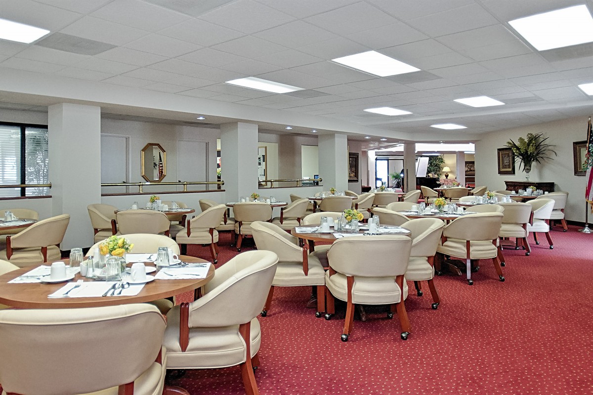 An elegant restaurant dining area with neatly arranged tables and chairs on a red carpet.
