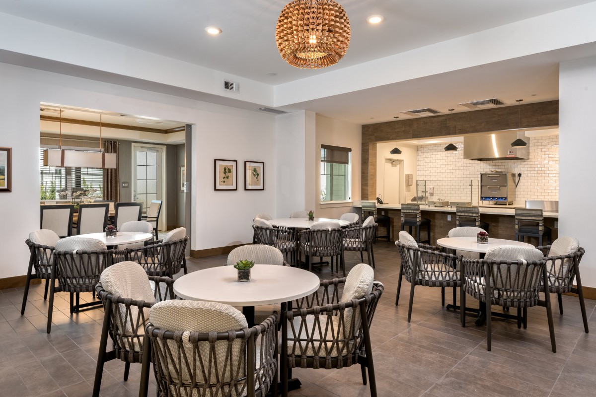 A modern dining area featuring round tables, comfortable chairs, and stylish pendant lighting.