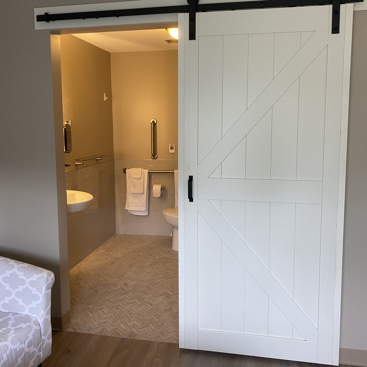 A modern bathroom with a white sliding barn door.