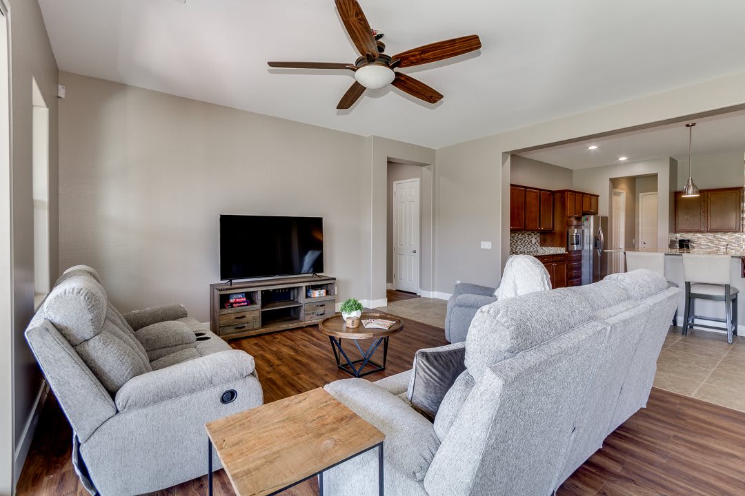 A modern living room with a comfortable sofa, TV, and ceiling fan.