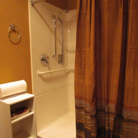 A bathroom with a shower and bathtub combination, featuring a brown shower curtain and nearby towel rack.