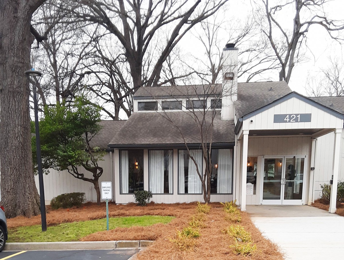 A quaint house surrounded by trees with a visible chimney and landscaped yard.