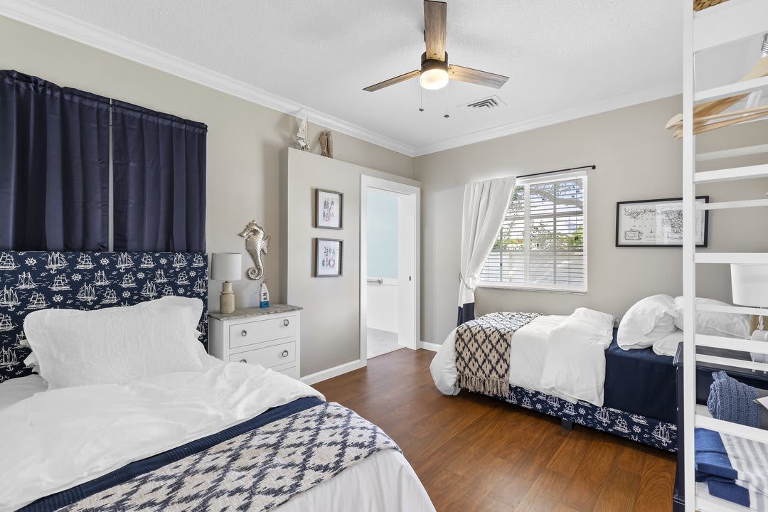 A cozy bedroom with twin beds, elegant decor, and warm wooden flooring.