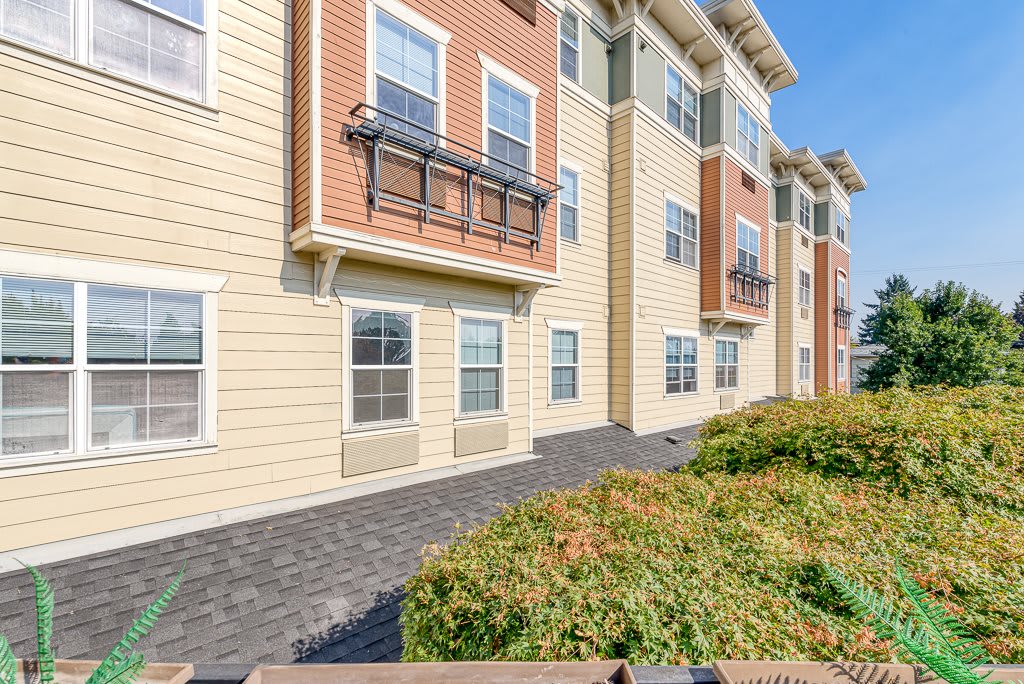 A modern apartment building with well-maintained landscaping on a clear day.
