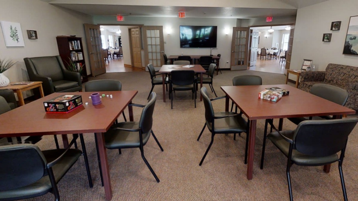 A communal room with tables, chairs, and a television, designed for gatherings or activities.