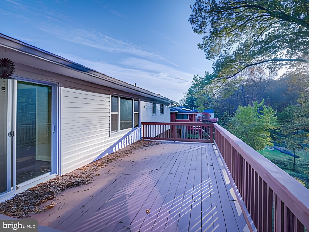 A spacious wooden deck attached to a house, surrounded by trees and nature.