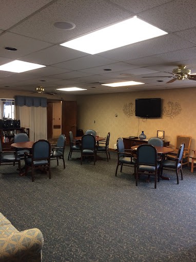 A dining area with several tables and chairs, a television on the wall, and decorative items.