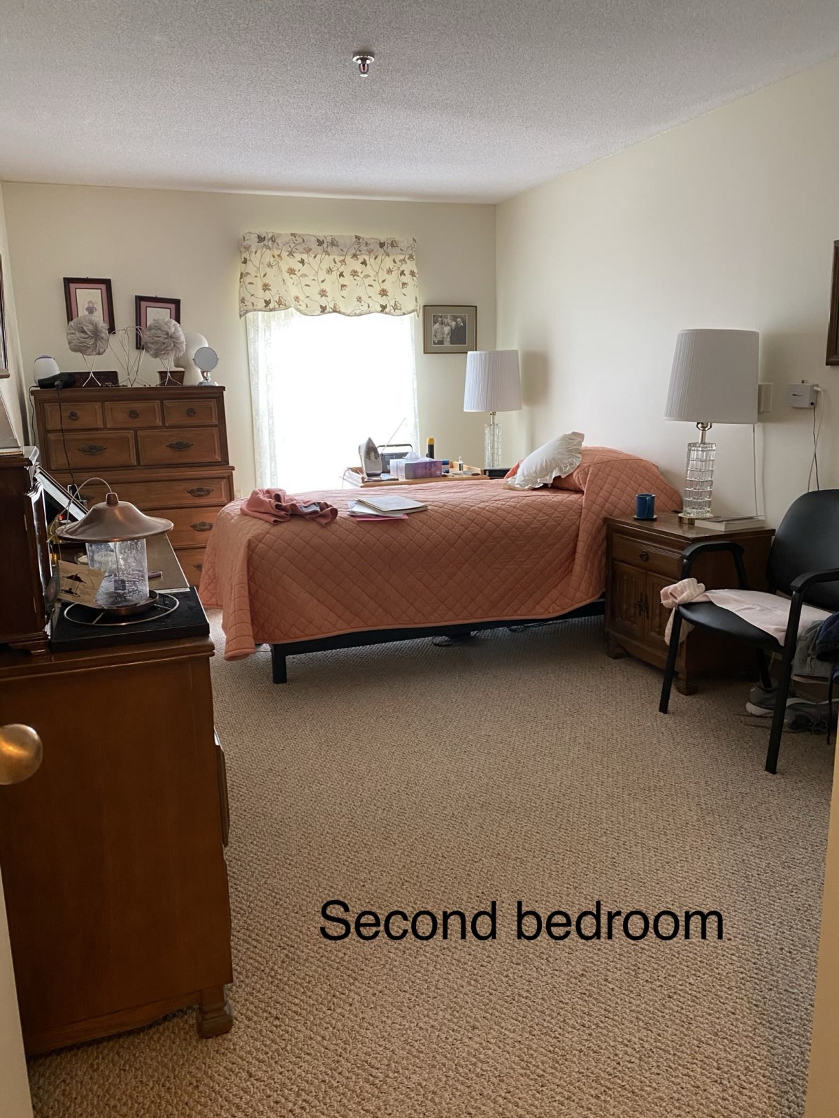A cozy second bedroom with a neatly made bed and wooden furniture.